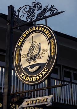 Close-up of the Microbrasserie Tadoussac sign featuring a ship and whale motif, captured outdoors at sunset.
