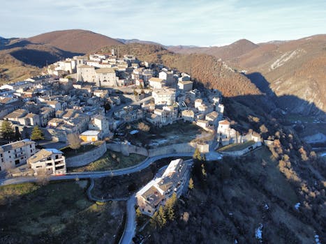Aerial view of a charming Italian village nestled in rolling hills, showcasing traditional architecture.
