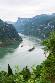 Aerial view of ships on Yangtze River surrounded by lush mountains in Yichang, China.
